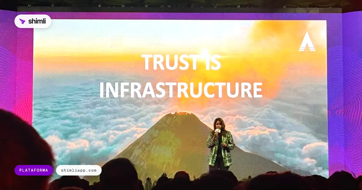 Pantalla gigante con la frase Trust is infrastructure sobre un volcán, y una ponente en el escenario del Volcano Summit 2026