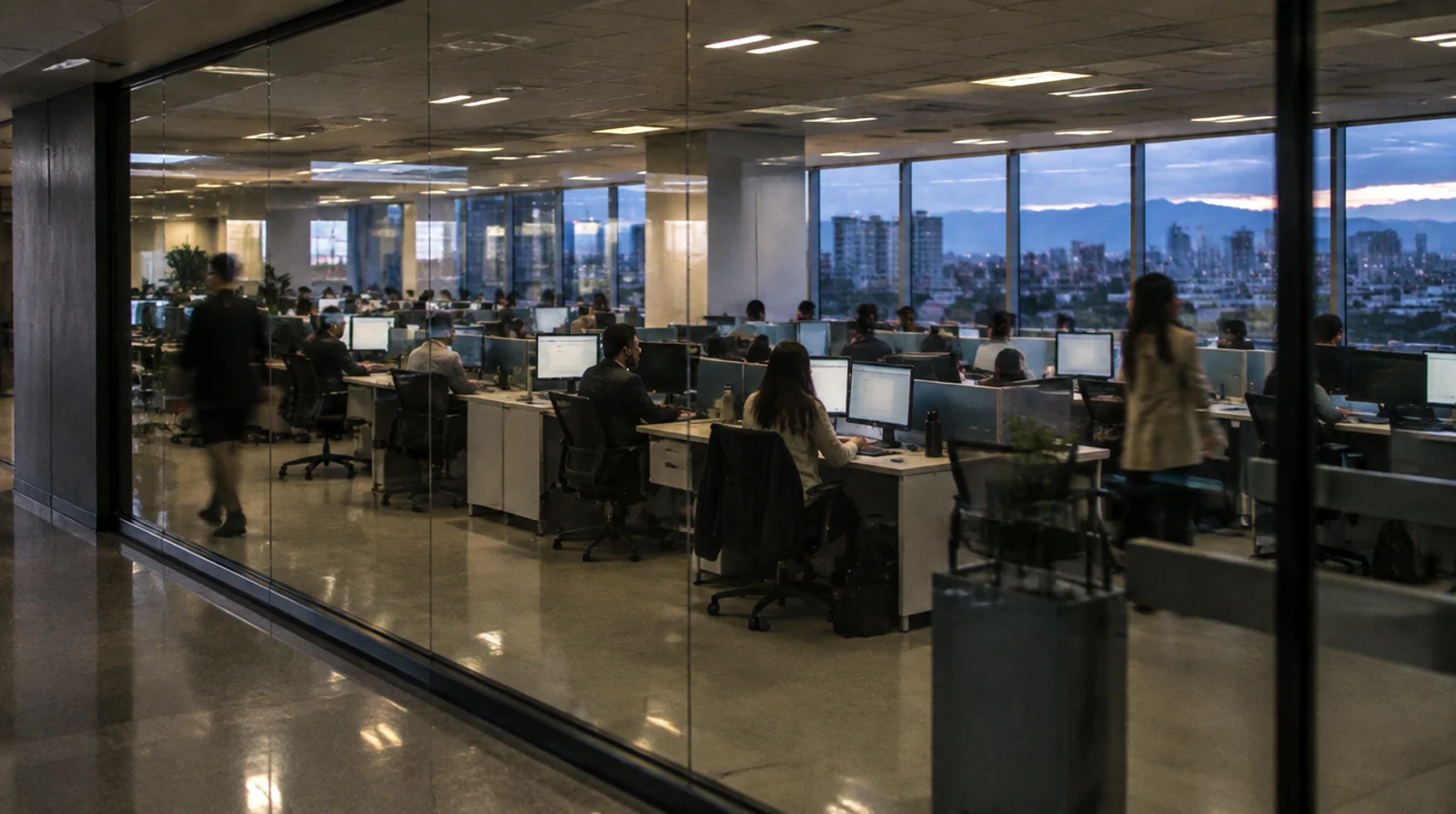 A bank's customer operations floor at dusk, seen through a glass partition