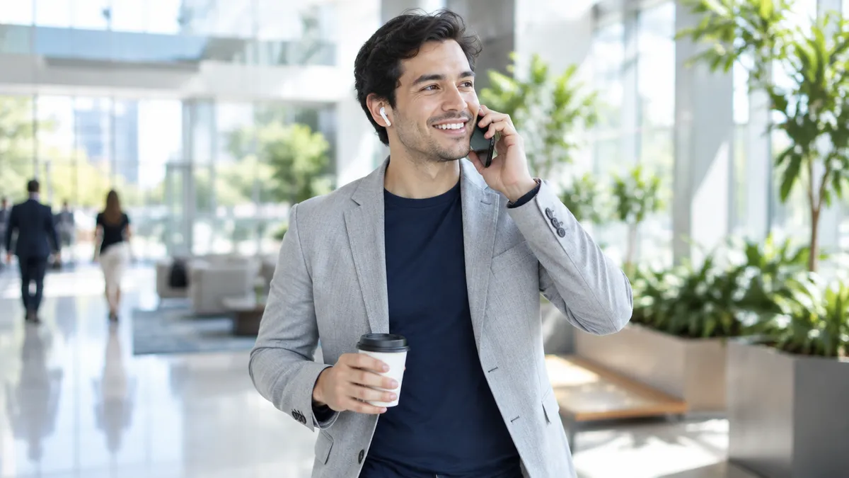 An account executive talks on the phone while crossing his office lobby